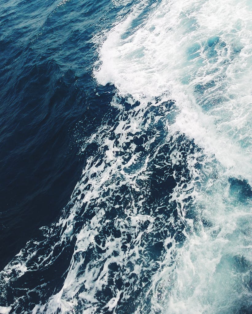 A dramatic aerial shot of ocean waves crashing, showcasing the vibrant blue sea off Cambodia's coast.